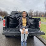 One person sitting on the back of a pickup truck that holds bags of gifts provided by generous Gifts for All God's Children donors
