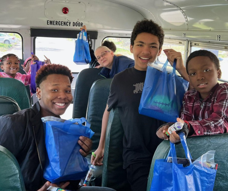 GFAGC_Easter_1 Children inside a bus hold up their Easter Bags and smile